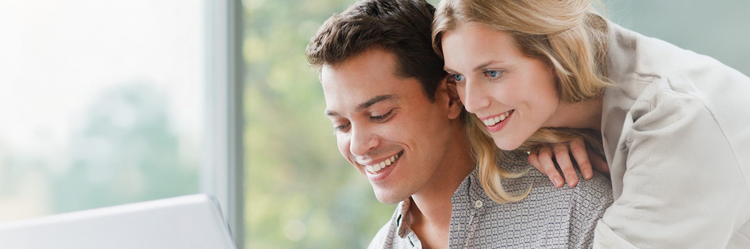 Lächelndes Paar schaut gemeinsam auf einen Laptop